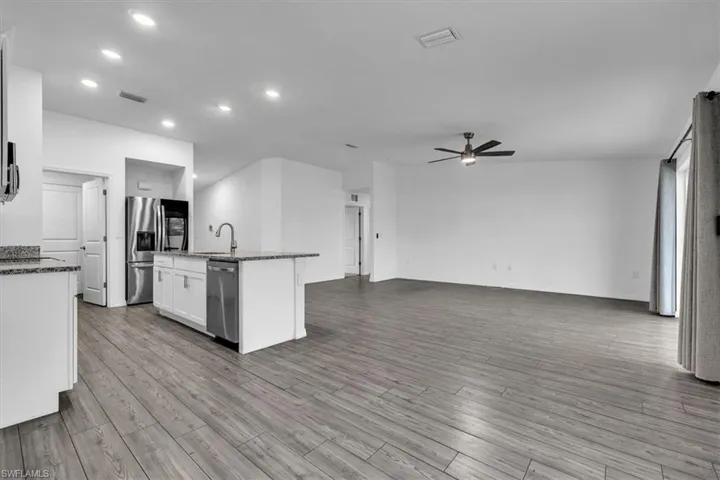 Empty room featuring a ceiling fan and light carpet