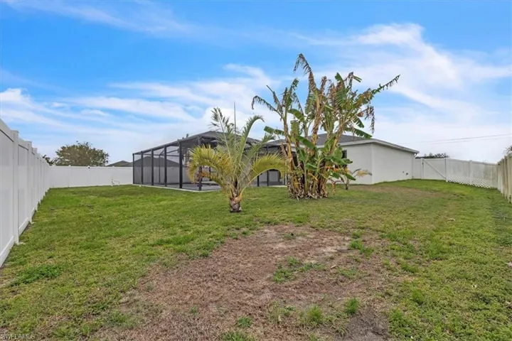 Fenced backyard with a sunroom, glass enclosure, and a gate
