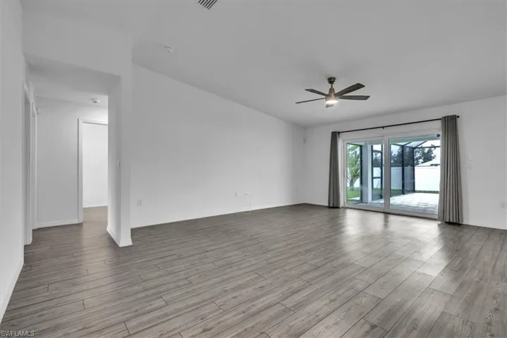 Unfurnished living room featuring ceiling fan and dark wood-type flooring