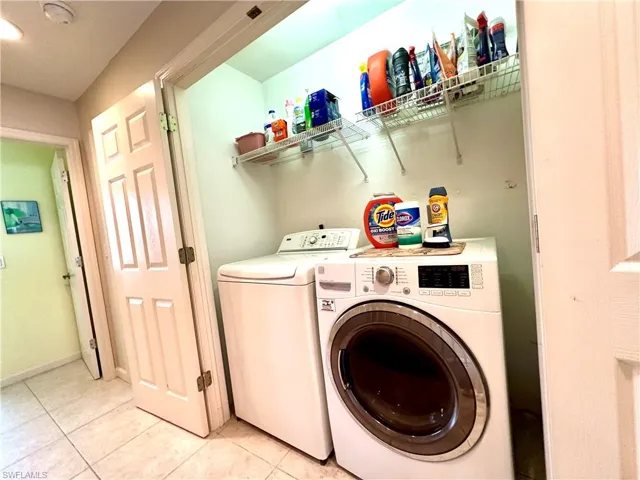 Laundry area featuring washing machine and clothes dryer and storage shelving.