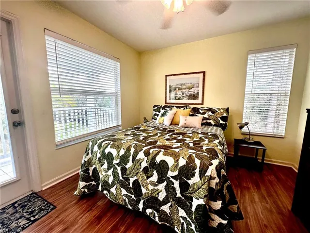 Third level guest Bedroom with multiple windows, dark luxury vinyl flooring, access to deck and ceiling fan.