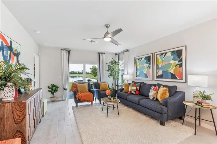 Living room featuring ceiling fan, light wood-type flooring, and a water view