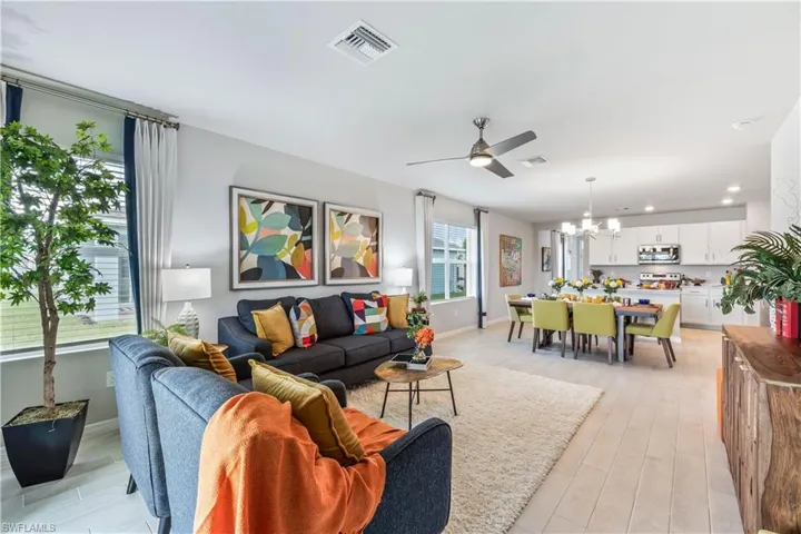 Living room with ceiling fan with notable chandelier and light hardwood / wood-style floors