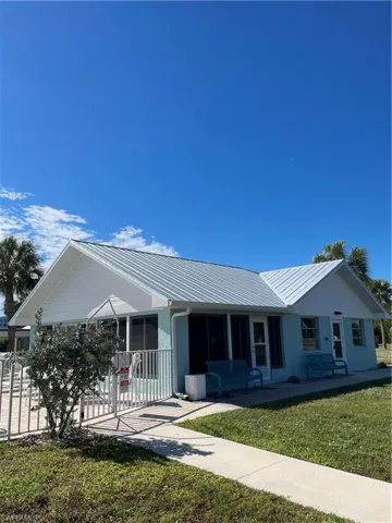 Ranch-style home with a metal roof, a front lawn, and covered porch