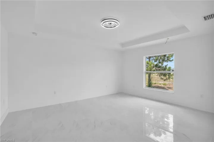Unfurnished room with tile floors and a tray ceiling