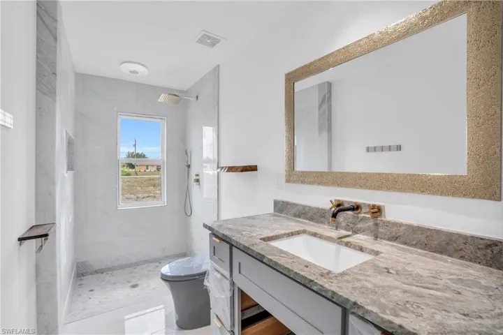 Bathroom with a tile shower, vanity, and toilet