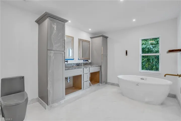 Bathroom featuring a bath, tile flooring, vanity, and toilet