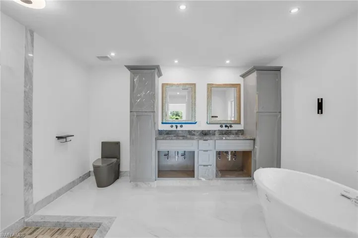 Bathroom featuring tile flooring, vanity, and a bath