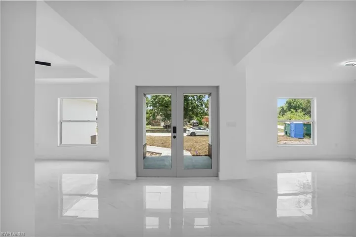 Tiled empty room featuring french doors