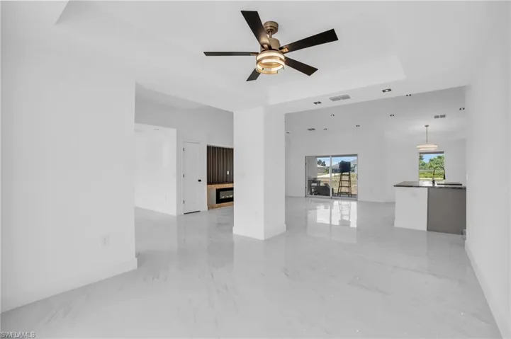 Tiled empty room featuring ceiling fan and a raised ceiling