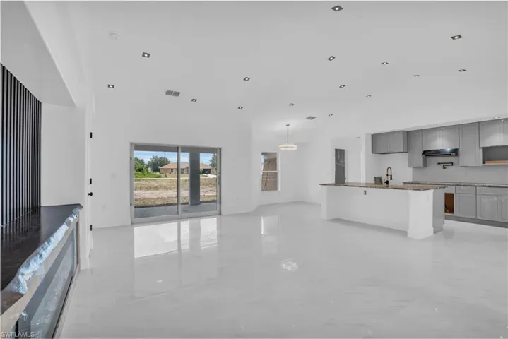 Unfurnished living room featuring a high ceiling, sink, and light tile flooring