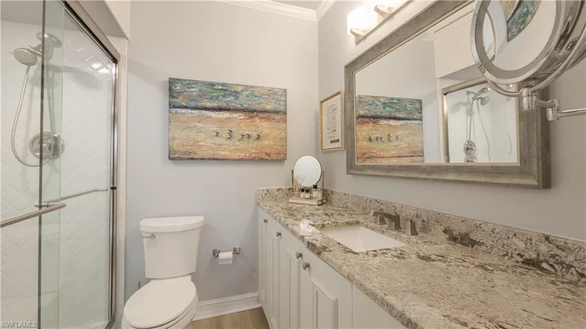 A more intimate view of the ensuite master bathroom with/granite counter top, designer inspired cabinets touches, mirror, light fixture, Kohler toilet and more! There is a custom tile feature, semi-frameless glass doors, and a light in the shower.