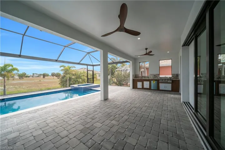 View of swimming pool featuring glass enclosure, area for grilling, a patio, a sunroom, and a pool with connected hot tub