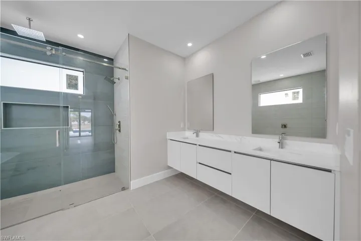 Full bath featuring double vanity, a stall shower, light tile patterned floors, and recessed lighting