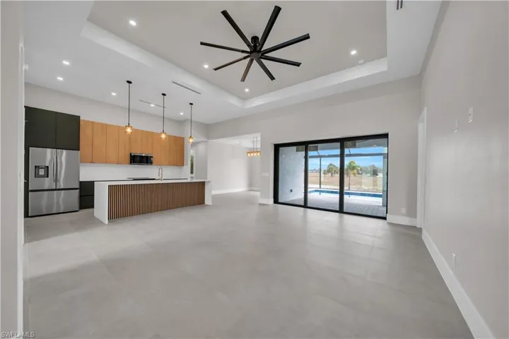 Kitchen with light countertops, modern cabinets, appliances with stainless steel finishes, open floor plan, and a ceiling fan
