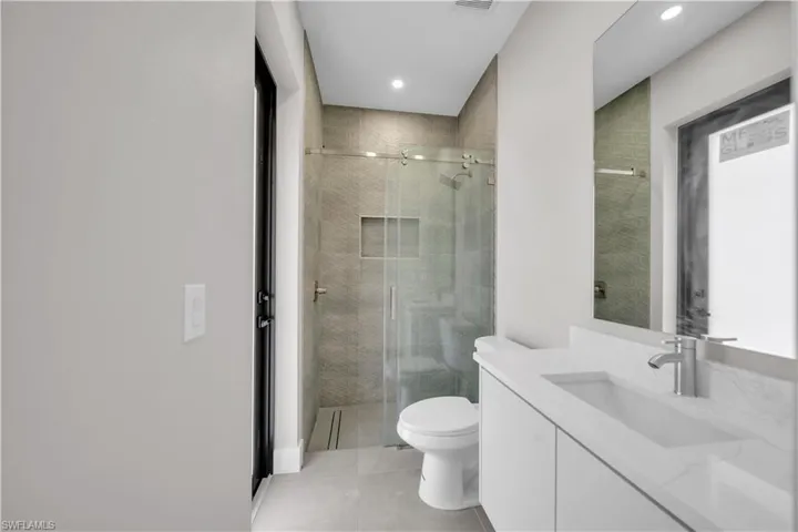 Full bathroom featuring vanity, a stall shower, light tile patterned floors, and recessed lighting