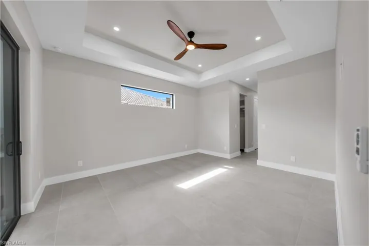 Empty room with ceiling fan, recessed lighting, and a raised ceiling
