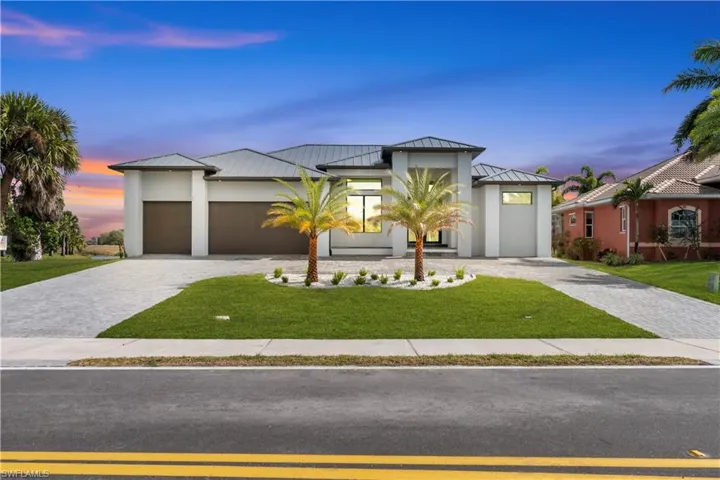 Modern home featuring a standing seam roof, a metal roof, a front yard, decorative driveway, and a garage