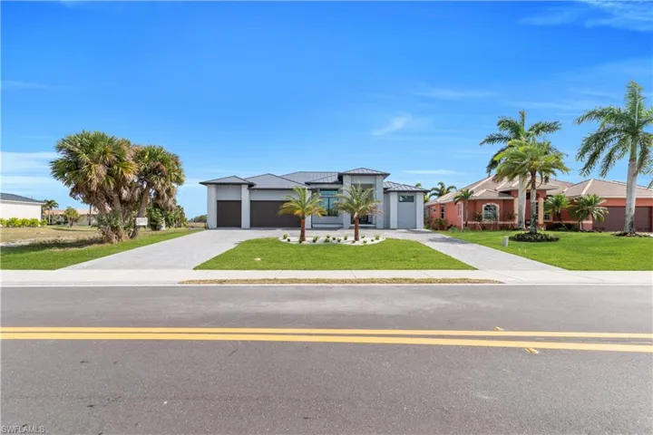 View of front of property with a front yard, decorative driveway, an attached garage, and a metal roof