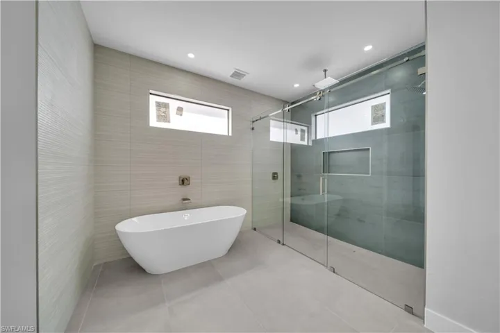 Full bathroom with tile walls, a shower stall, a soaking tub, recessed lighting, and tile patterned flooring