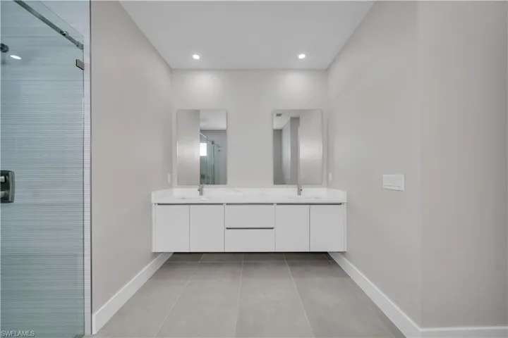 Bathroom with a stall shower, double vanity, and recessed lighting