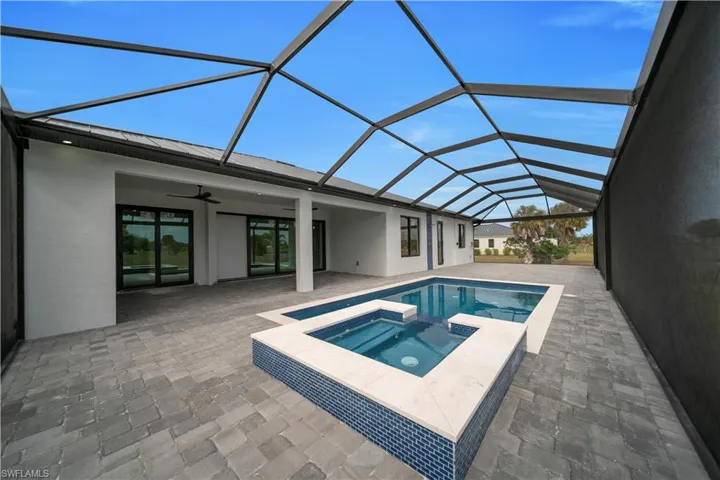 View of swimming pool with a sunroom, a patio, a pool with connected hot tub, and glass enclosure