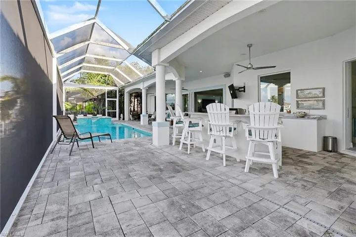 View of pool featuring a patio area, a sunroom, a pool with connected hot tub, and glass enclosure