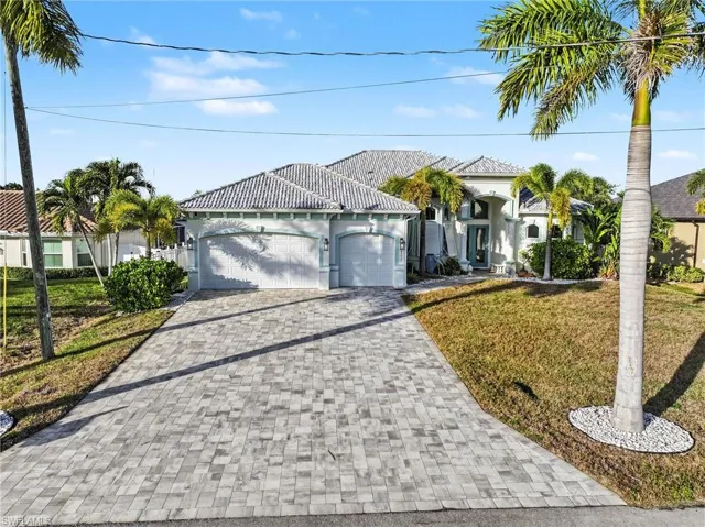 View of front facade featuring a front lawn, a garage, decorative driveway, and stucco siding
