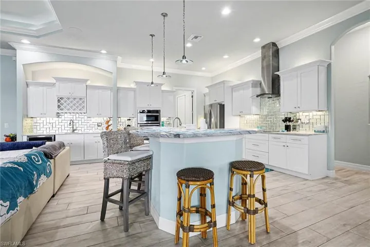 Kitchen featuring white cabinetry, a kitchen breakfast bar, ornamental molding, decorative backsplash, and recessed lighting