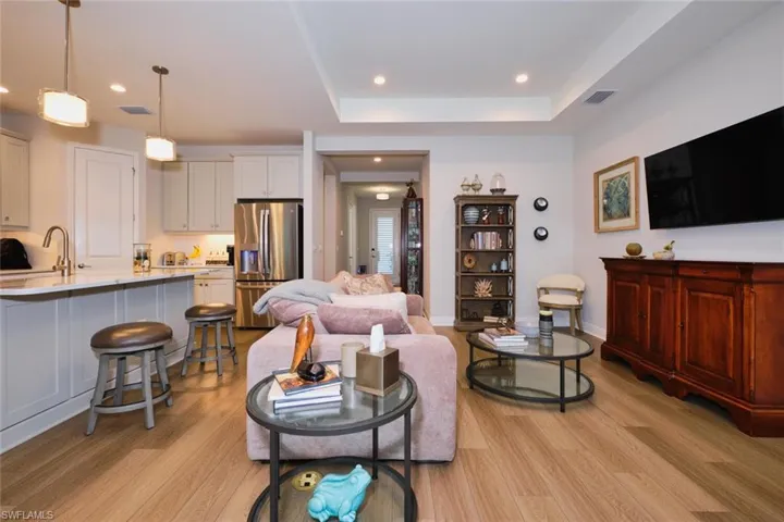 Living area featuring a raised ceiling, light wood finished floors, and recessed lighting