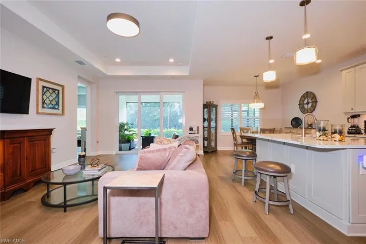 Living room featuring a raised ceiling, light wood-style flooring, and recessed lighting
