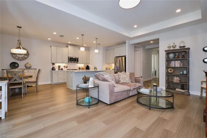 Living room with a tray ceiling, light wood finished floors, and recessed lighting