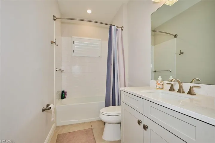 Bathroom with vanity, shower / tub combo with curtain, and light tile patterned floors
