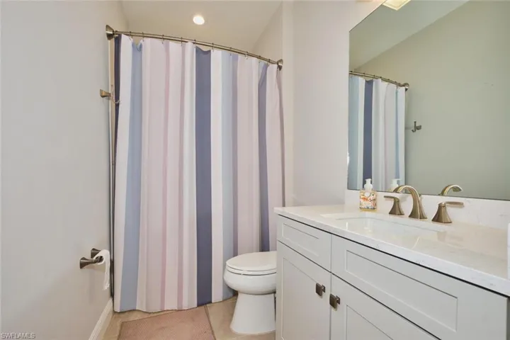 Full bathroom featuring vanity, curtained shower, light tile patterned floors, and recessed lighting