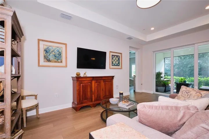 Living room featuring light wood-style flooring, recessed lighting, and a tray ceiling