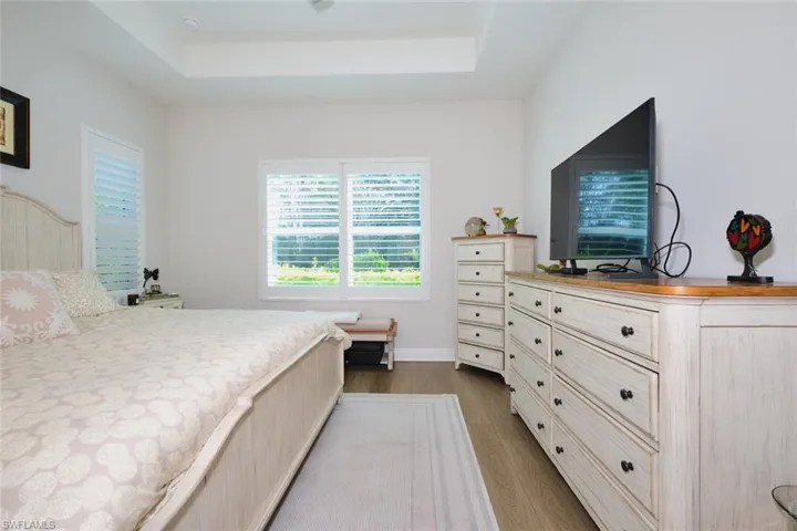 Bedroom with dark wood-style floors and a tray ceiling