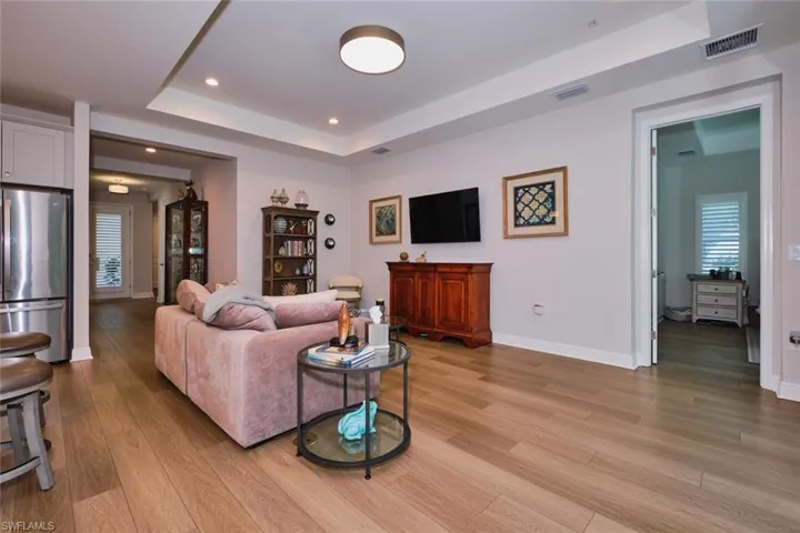 Living area with a tray ceiling, light wood-type flooring, and recessed lighting