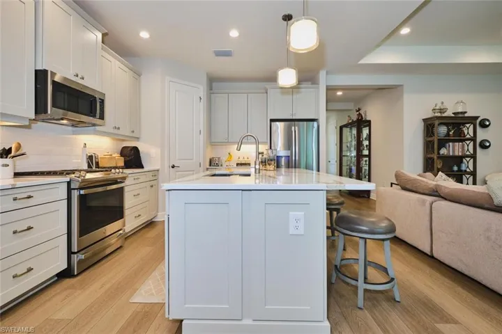 Kitchen featuring open floor plan, appliances with stainless steel finishes, light wood-style flooring, hanging light fixtures, and recessed lighting
