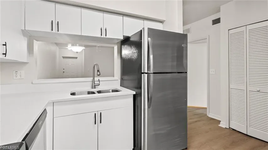 Kitchen featuring appliances with stainless steel finishes, white cabinets, and light wood-style flooring
