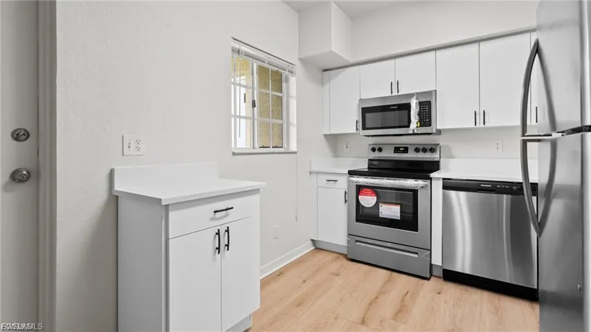 Kitchen featuring appliances with stainless steel finishes, light countertops, white cabinets, and light wood finished floors