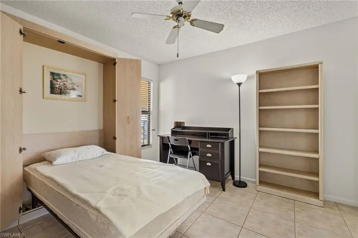 Bedroom with tile patterned flooring, ceiling fan, and a textured ceiling