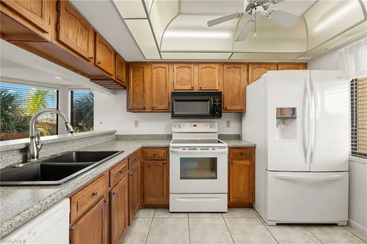 Kitchen featuring ceiling fan, sink, light tile patterned floors, and white appliances