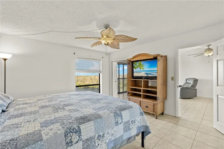 Bedroom featuring light tile patterned floors, a textured ceiling, access to outside, and ceiling fan
