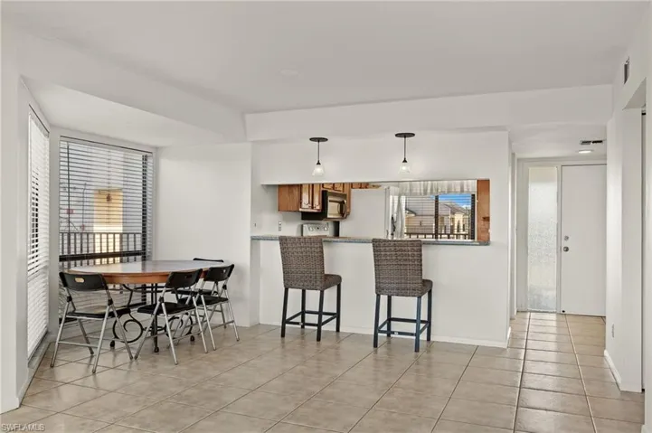 Kitchen featuring kitchen peninsula, light tile patterned floors, a healthy amount of sunlight, and white refrigerator