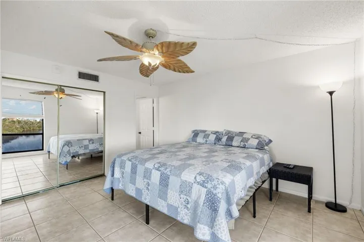 Bedroom with ceiling fan, a closet, light tile patterned floors, and a textured ceiling