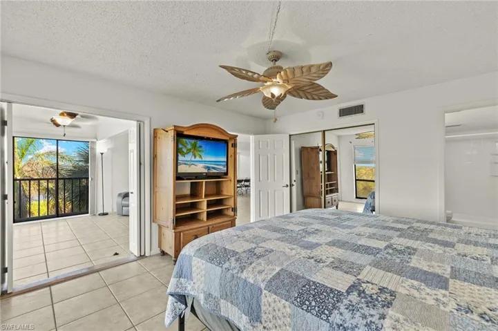 Tiled bedroom featuring ceiling fan, a textured ceiling, and a closet