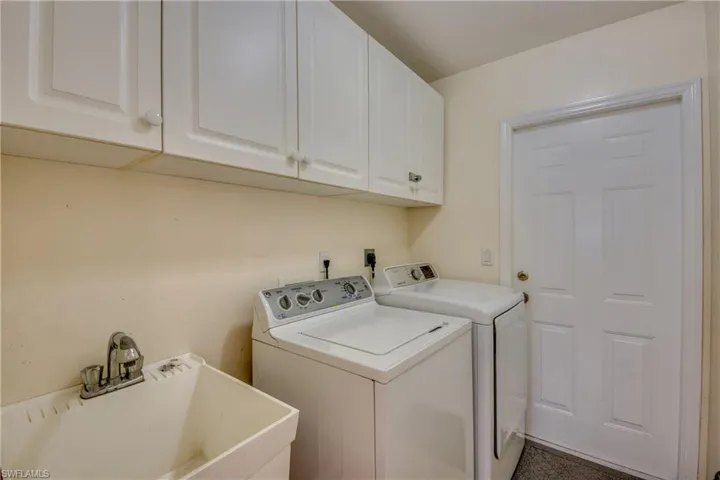 Clothes washing area featuring washer and clothes dryer, cabinets, and sink