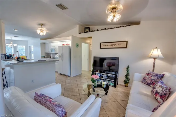Tiled living room featuring a chandelier and vaulted ceiling