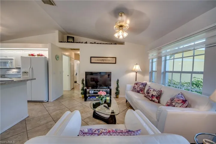 Tiled living room with ceiling fan and vaulted ceiling