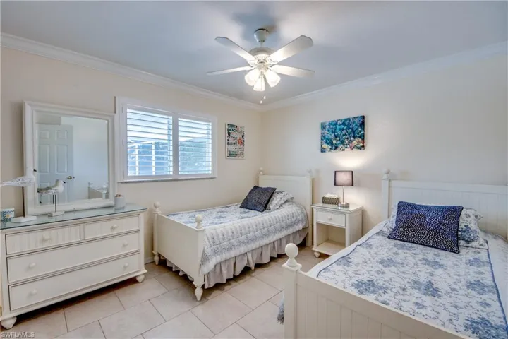 Bedroom featuring ceiling fan, light tile patterned floors, and crown molding